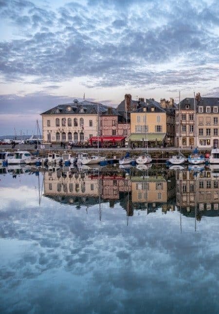Reflet des bâtiments dans l'eau à Honfleur, créant une harmonie entre l'architecture et la nature environnante