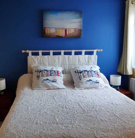 Un lit blanc avec deux oreillers, situé dans une chambre d'hôtes accueillante